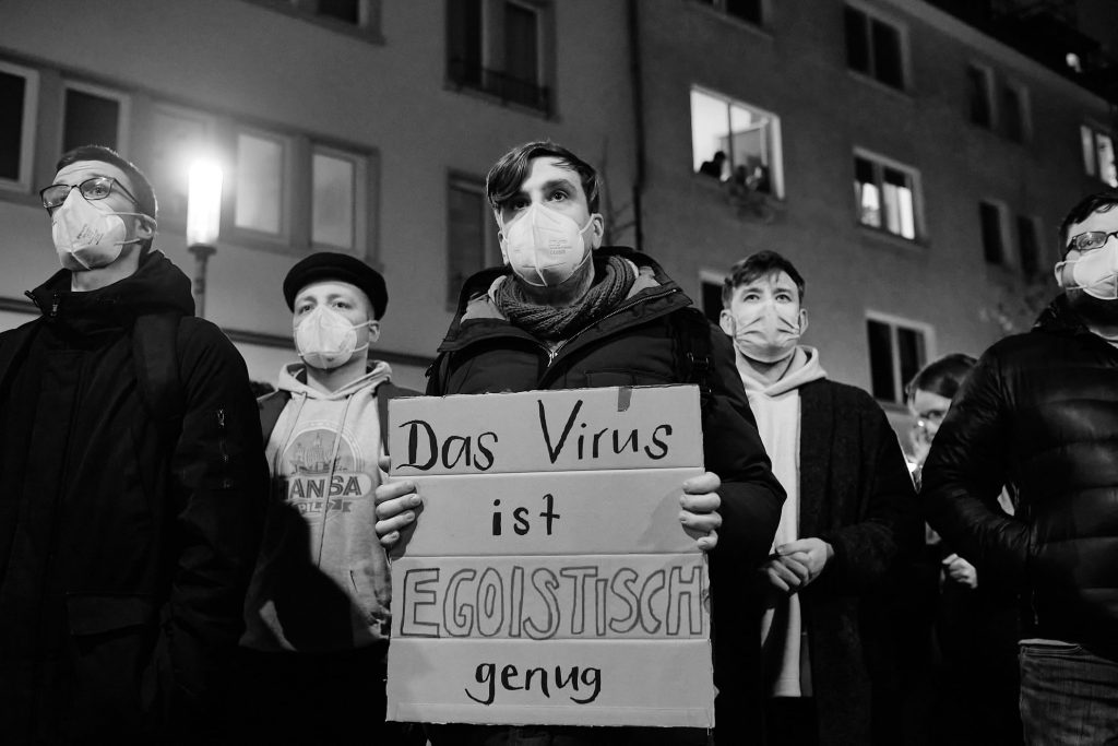 Fünf junge Demonstranten. Der mittlere hält ein Schild mit der Aufschrift „Das Virus ist egoistisch genug!“