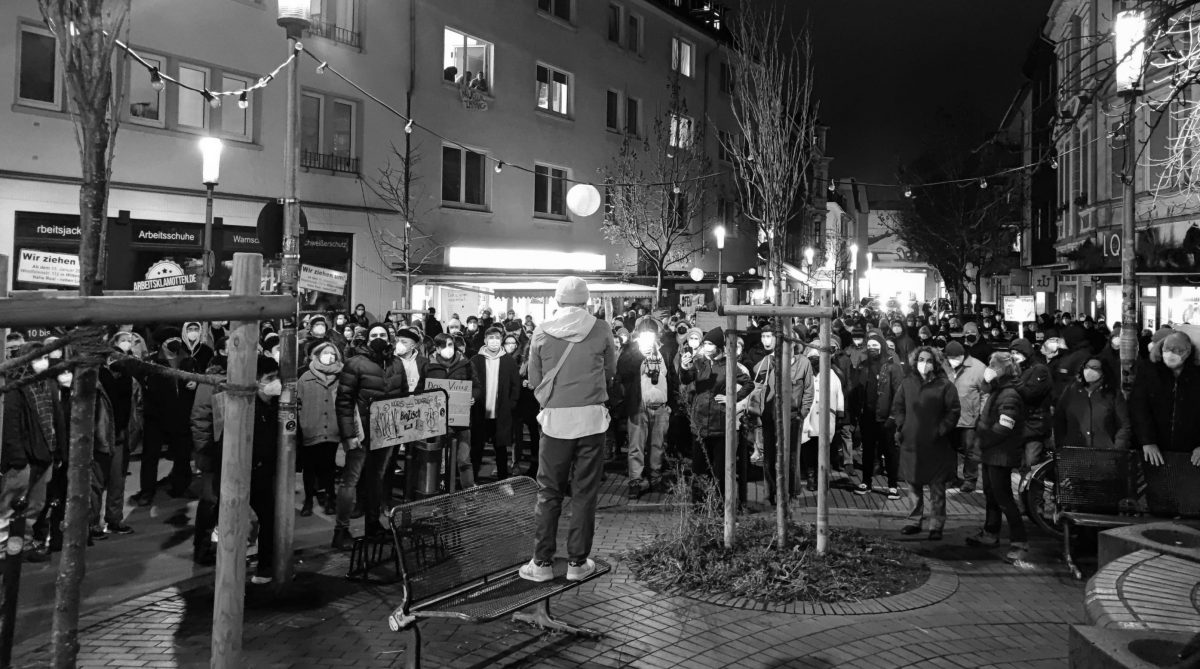 Knut Szmit von hinten, während er seine Rede hält. Vor ihm die Versammlung, die die gesammte Wiesenstraße vom Brunnen bis zum Ende einnimmt.